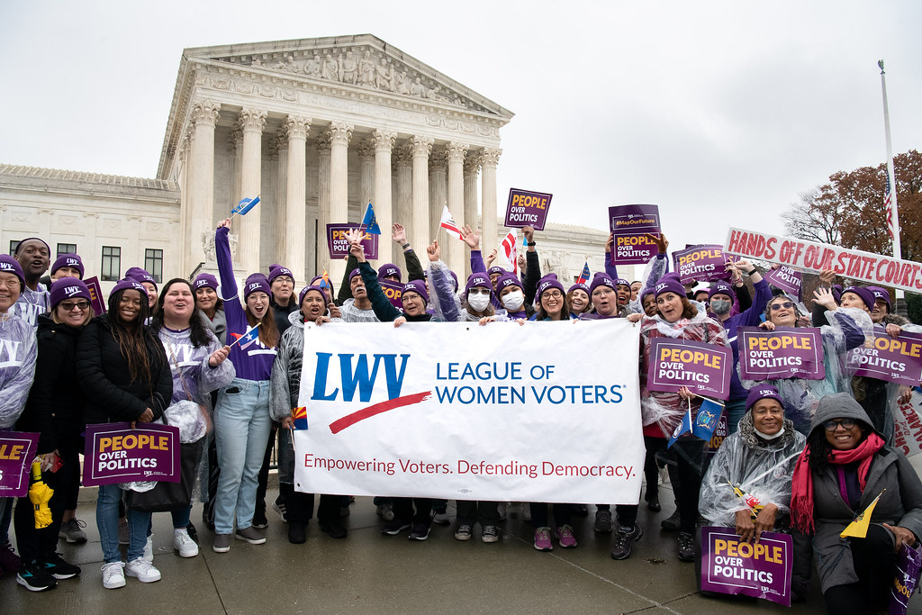 Protesters in front of Supreme Court with LWV sign